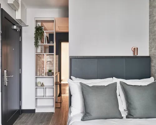 Bed pillows and shelving unit studio bedroom at ARK Canary Wharf in London Student Accommodation