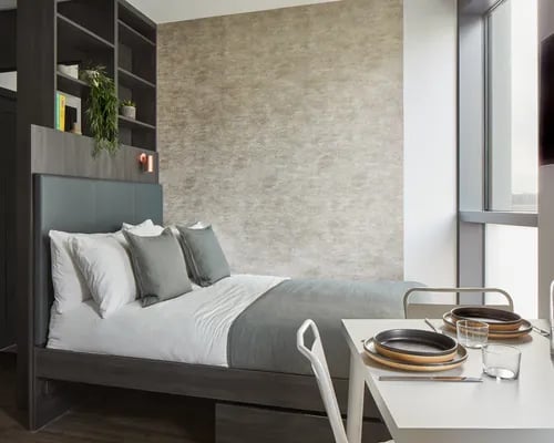 Bed with pillows and shelves dining table bedroom at ARK Canary Wharf in London Student Accommodation