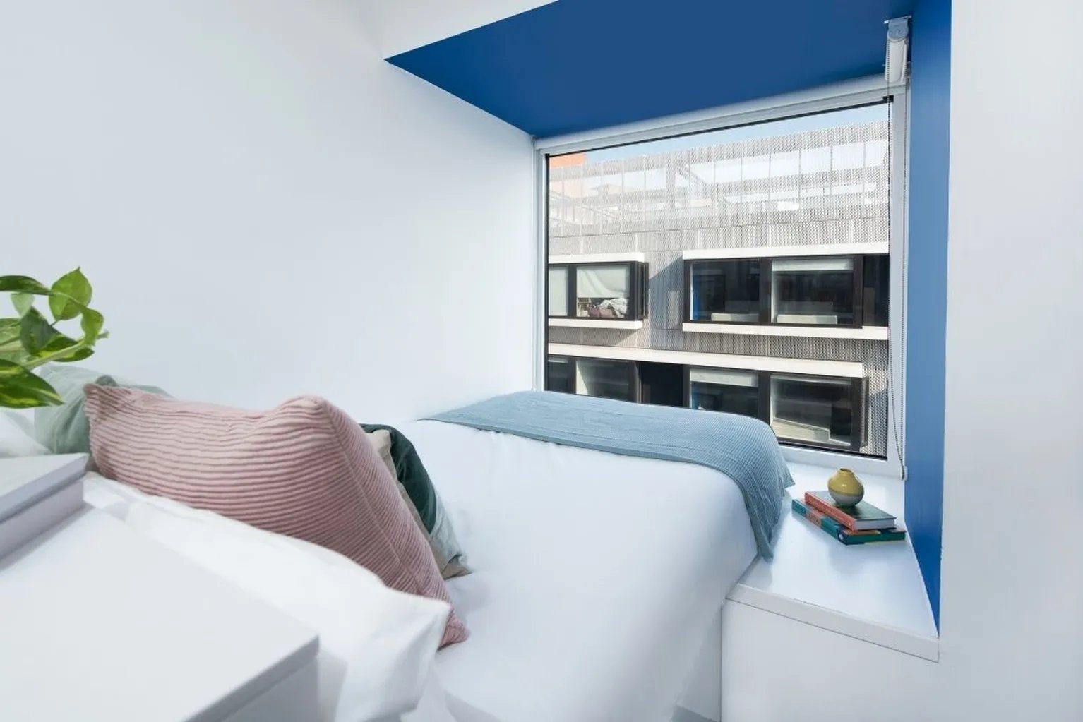 Bed with pillows and blue throw bedroom at Scape Shoreditch in London Student Accommodation