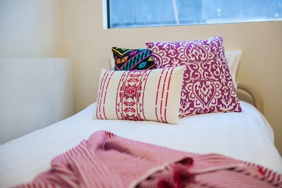 Decorative pillows on white bed with pink blanket bedroom at Student Living On ABeckett in Melbourne Student Accommodation