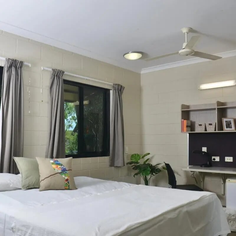 Bed with pillows window study area and shelves bedroom at CDU Village Casuarina in Darwin Student Accommodation