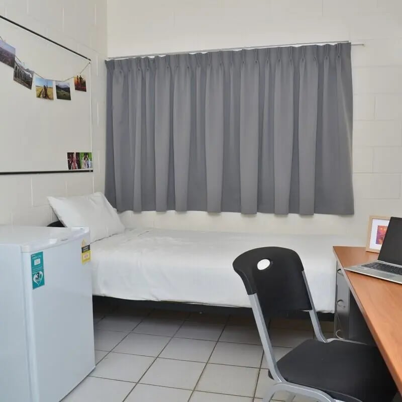 Bed with photos mini fridge desk chair bedroom at CDU Village Casuarina in Darwin Student Accommodation