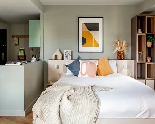 Bed with pillows art shelf and decorative vases bedroom at ARK Wembley in London Student Accommodation