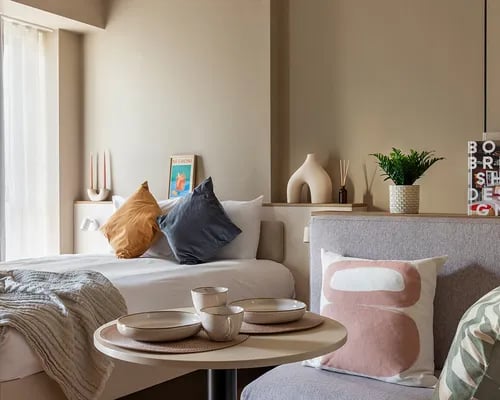 Bed pillows small table plant decorative vase bedroom at ARK Wembley in London Student Accommodation