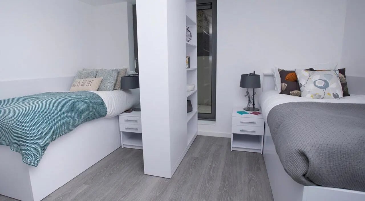 Two beds with white nightstands and lamps bedroom at The Cube Ealing in London Student Accommodation
