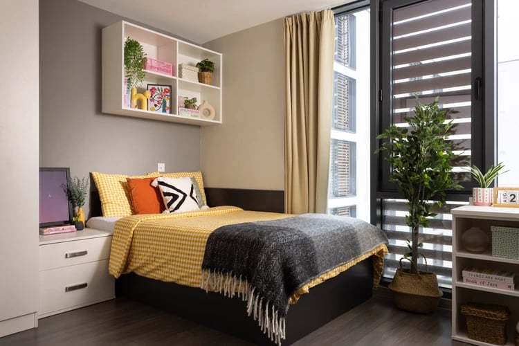 Bed with yellow checkered bedding bedside table and shelf Bedroom at Salisbury court in Edinburgh Student Accommodation