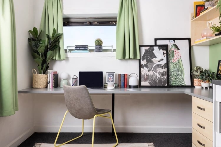 Desk with laptop chair artwork and plant study area at Sir Charles Groves Hall in Manchester Student Accommodation