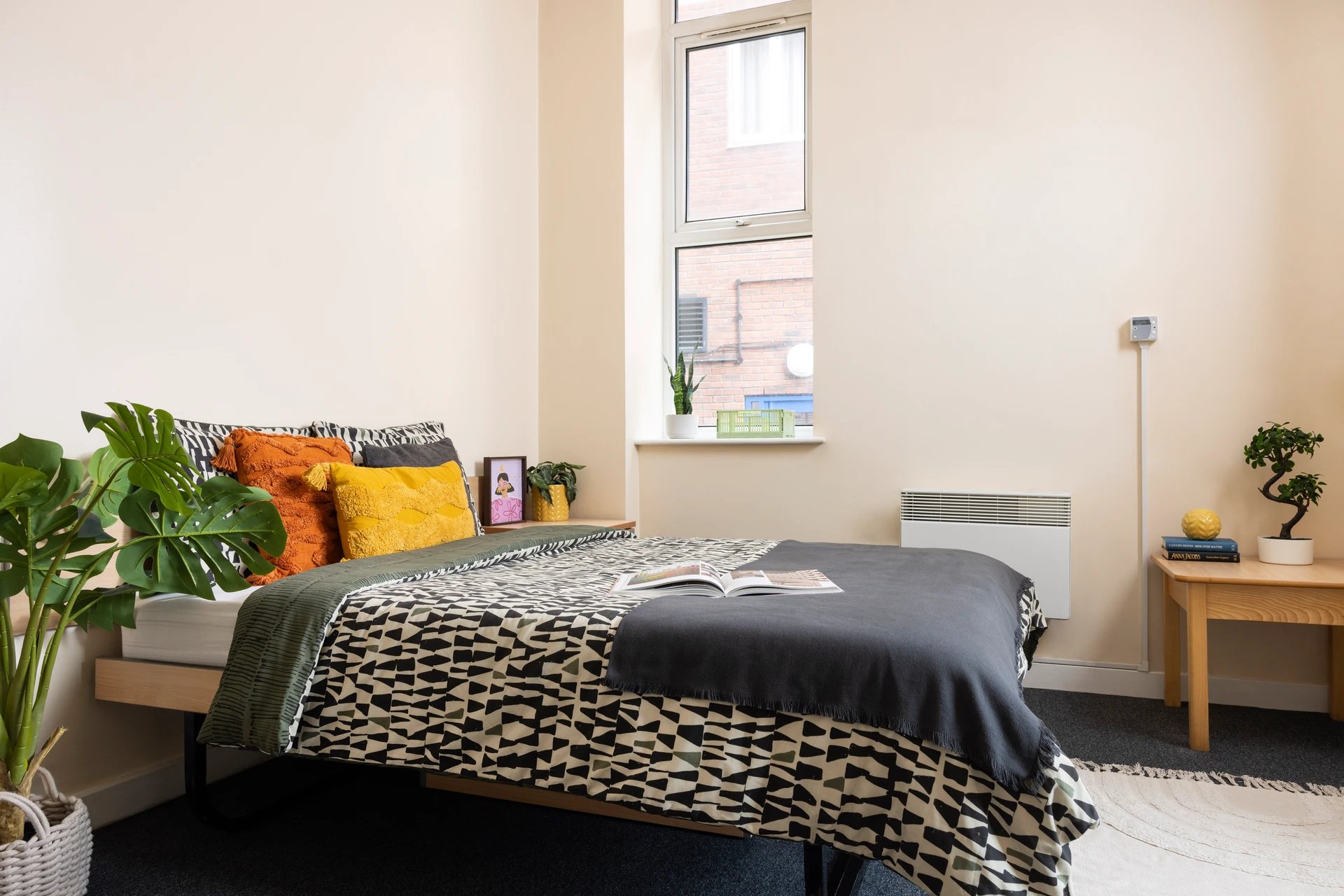 Bed with patterned duvet orange yellow pillows bedside table bedroom at Lennon Studios in Liverpool Student Accommodation