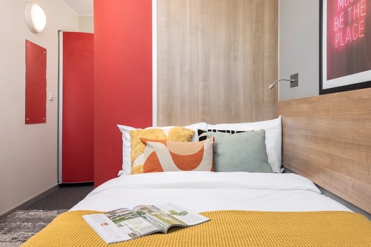 Bed pillows magazine and yellow blanket bedroom at Sky Plaza in Leeds Student Accommodation
