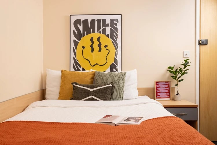 Bed with pillows artwork plant and bedside table bedroom at Lennon Studios in Liverpool Student Accommodation