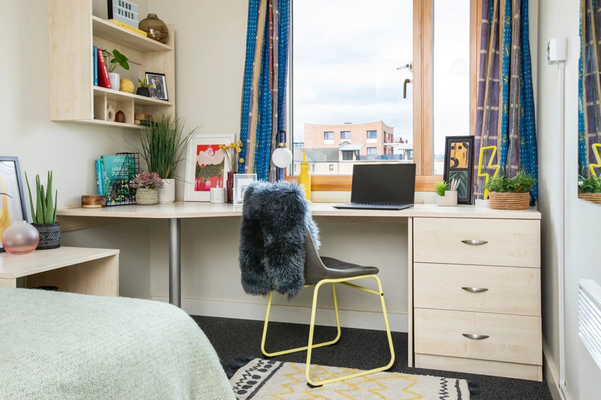 Desk with laptop books plants and a chair bedroom at Somerset Court in London Student Accommodation