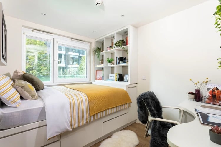 Bed desk shelving unit and pillows bedroom at Drapery Place in London Student Accommodation