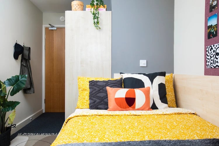 Bed with yellow bedding and patterned pillows bedroom at Beaumont Court in London Student Accommodation
