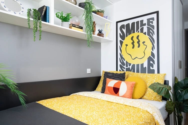 Bed with yellow bedding and smiley face poster bedroom at Morriss House in Nottingham Student Accommodation