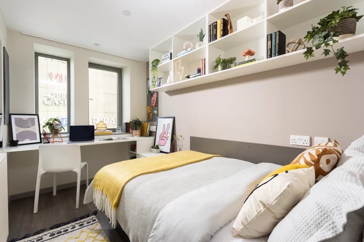 Desk with laptop bed with yellow blanket bedroom at Stratford One in London Student Accommodation