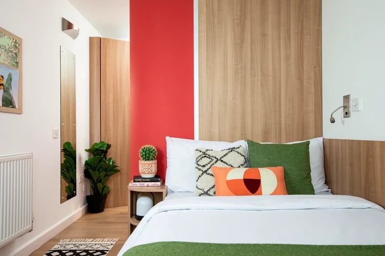 Bed with pillows plants and side table bedroom at North Lodge in London Student Accommodation