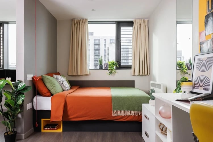Bed with orange and green blankets study desk bedroom at Olympic Way in London Student Accommodation