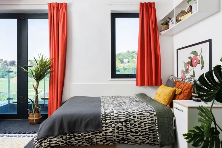 Bed with patterned duvet orange curtains bedroom at Elvet Studios in Durham Student Accommodation