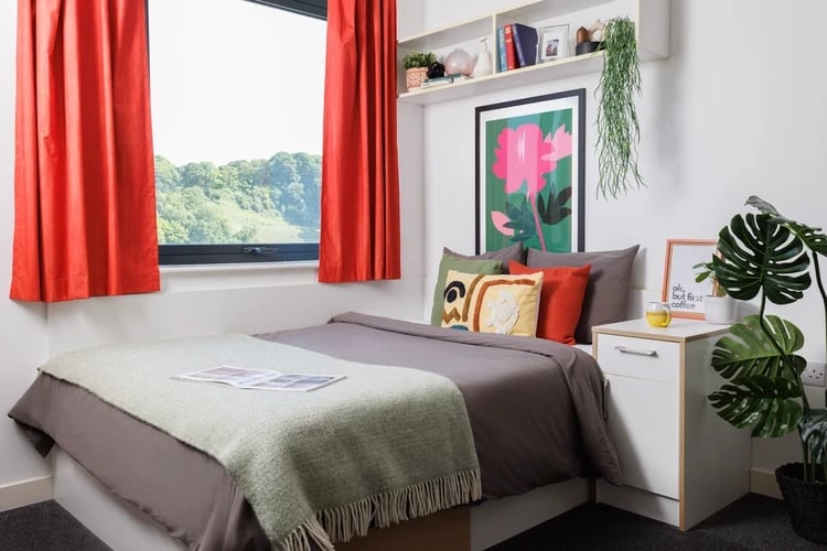 Bed with green throw and orange curtains bedroom at Elvet Studios in Durham Student Accommodation