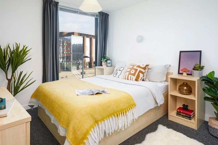 Bed with yellow blanket and pillows bedroom at Harriet Martineau in Birmingham Student Accommodation