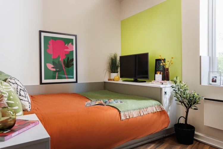 Orange bed green throw artwork television bedroom at Quay Point Studios in Newcastle Upon Tyne Student Accommodation