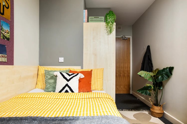 Yellow checkered bed with patterned pillows bedroom at Raglan House in Coventry Student Accommodation