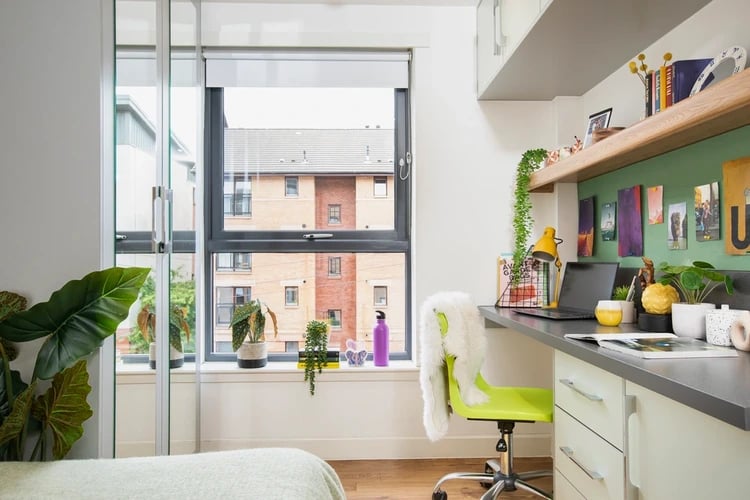 Desk with laptop plants chair and window study area at Tramworks in Glasgow Student Accommodation