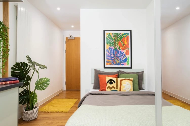 Bed with colorful pillows and art Bedroom at Tramworks in Glasgow Student Accommodation