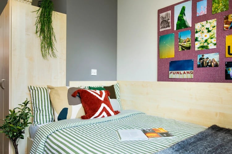 Bed with striped duvet and wall art bedroom at Rahere Court in London Student Accommodation