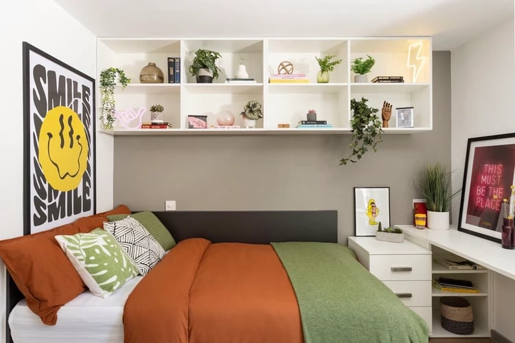 Bed with orange duvet green blanket shelves bedroom at Parkway Gate in Manchester Student Accommodation