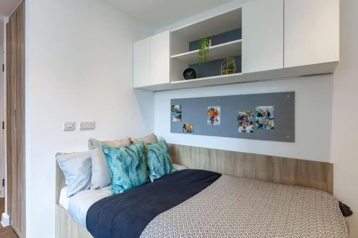 Bed with pillows and mounted shelves bedroom at Saltwater Place in Plymouth Student Accommodation