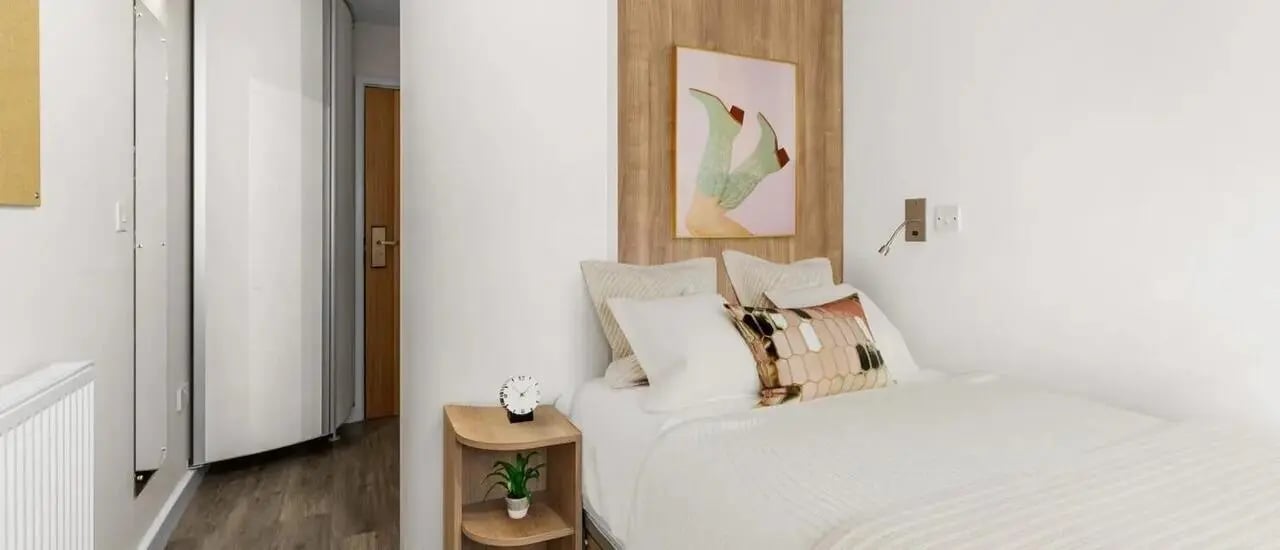 Bed pillows art bedside table plant bedroom at Chapter Islington in London Student Accommodation