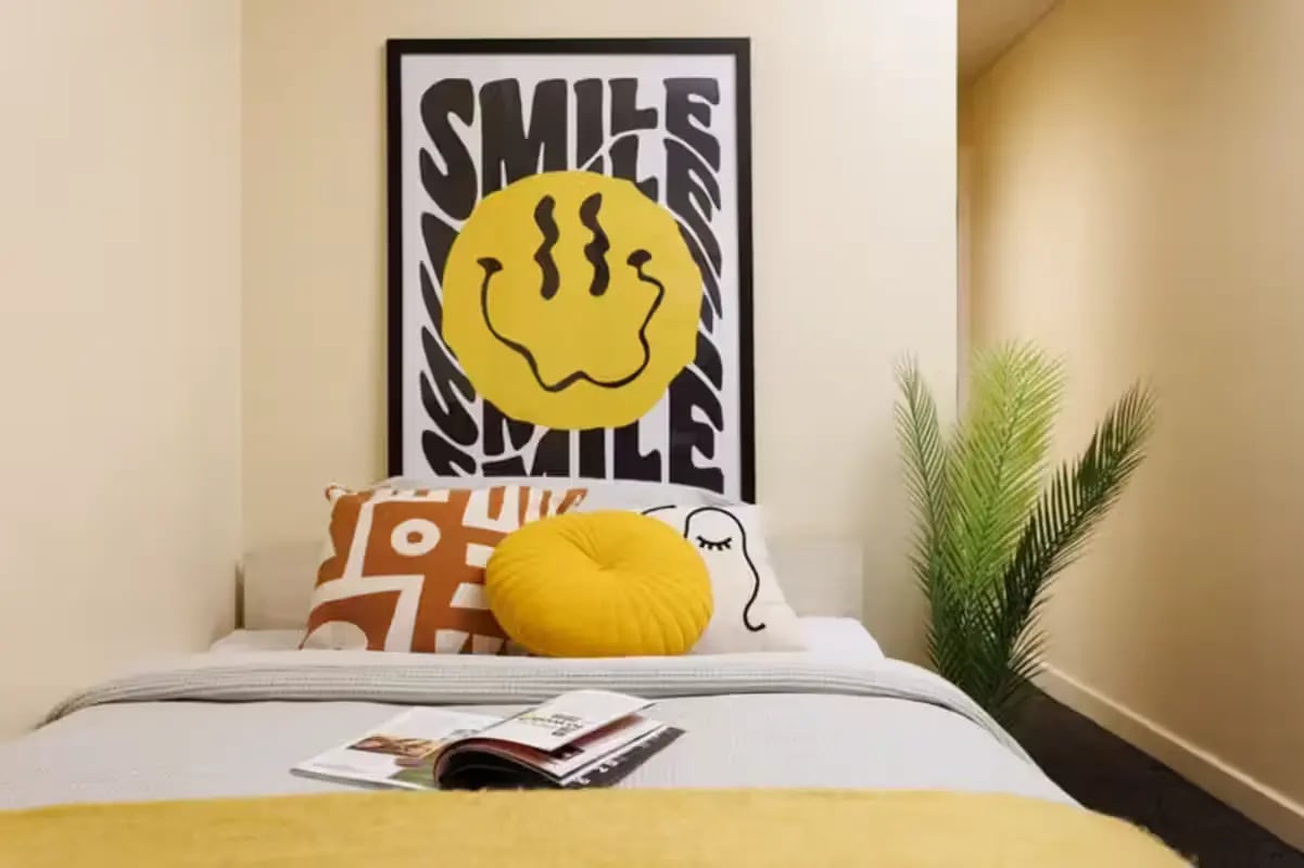 Bed with smile poster pillows plant bedroom at Curzon House in Nottingham Student Accommodation