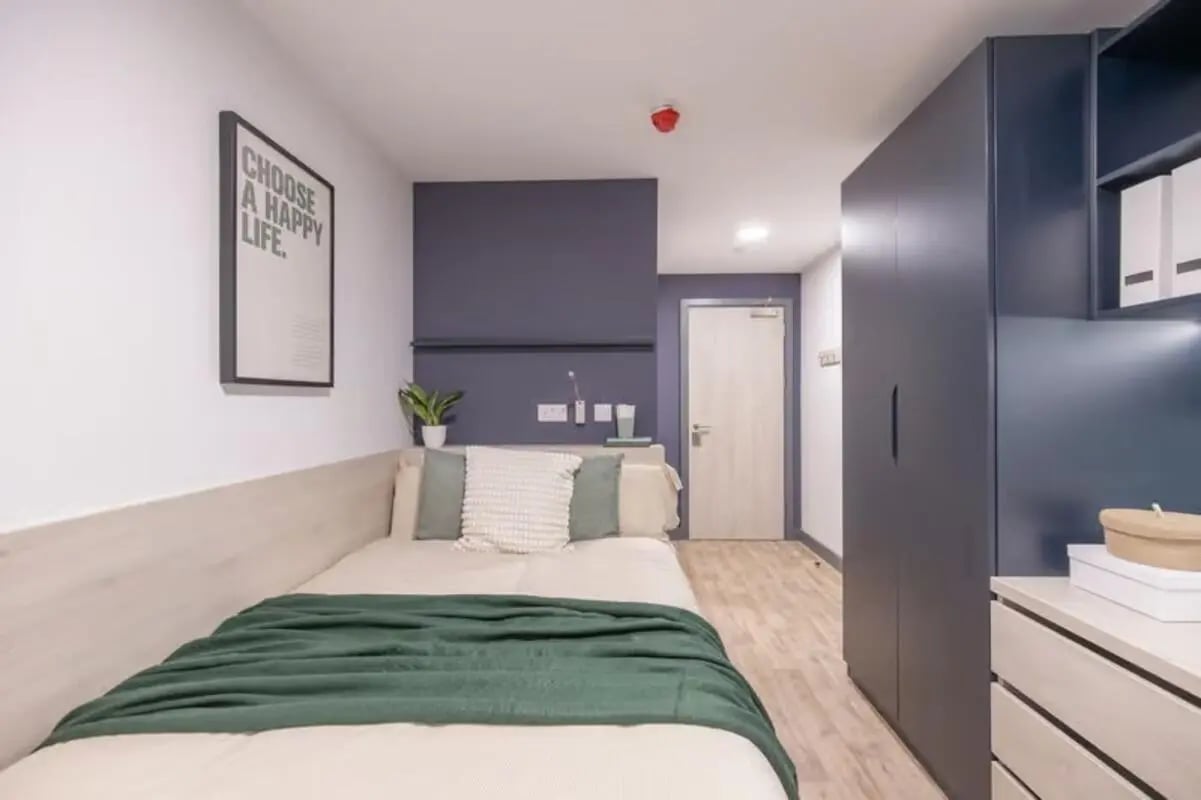 Bed with green blanket and pillows Bedroom at Tribeka in Leeds Student Accommodation