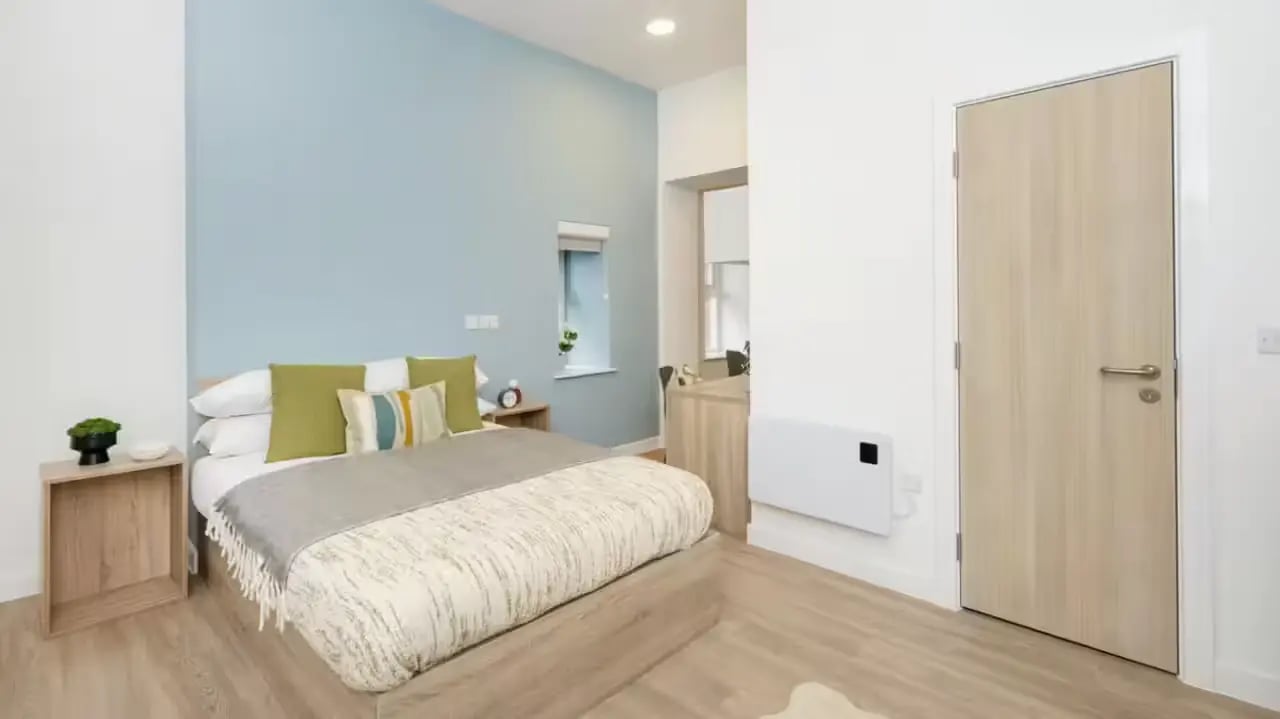 Bed with green pillows and bedside table bedroom at St Gabriels in Manchester Student Accommodation