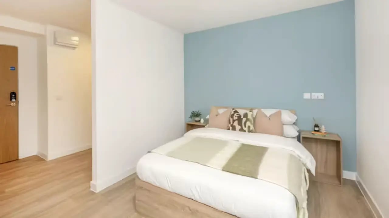 Bed and nightstand with blue wall bedroom at St Gabriels in Manchester Student Accommodation