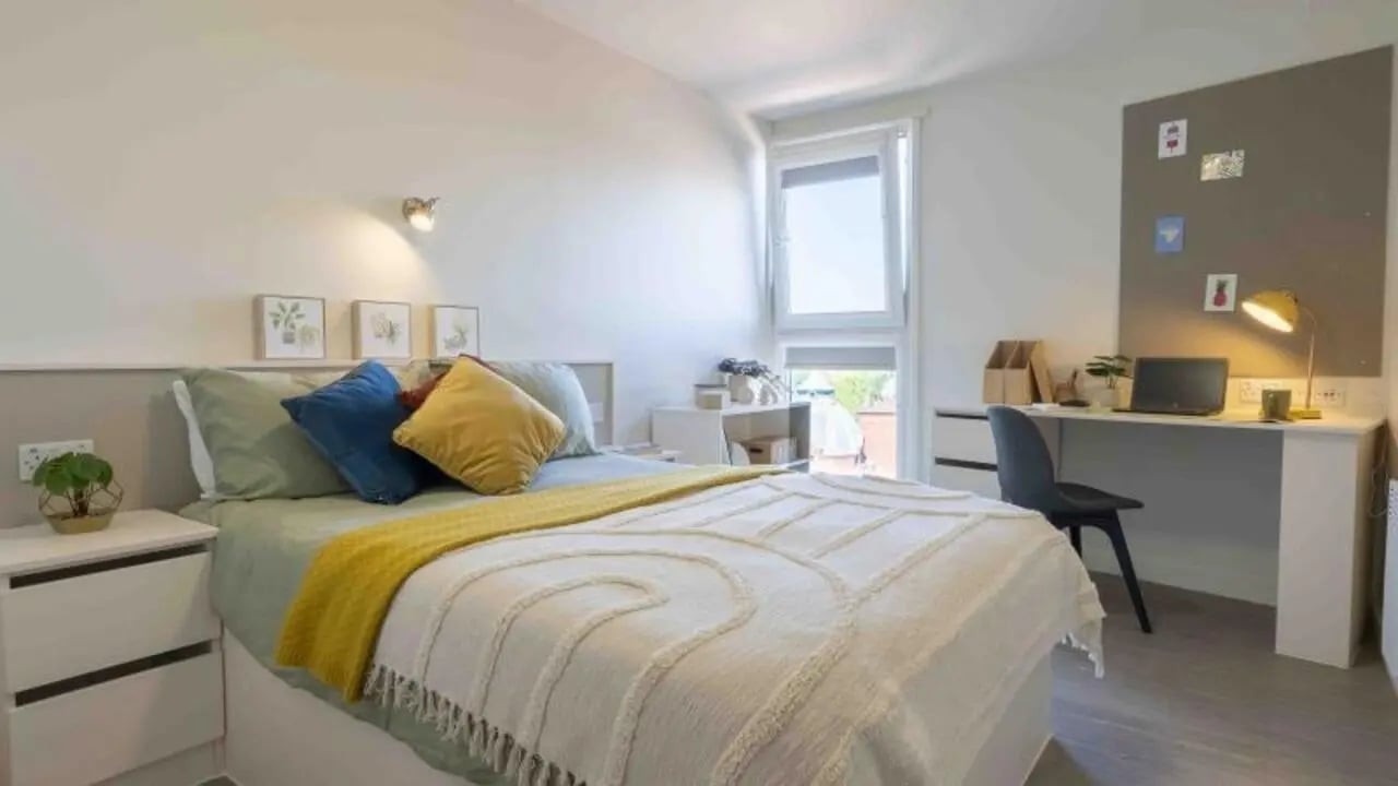 Bed pillows desk laptop lamp and bulletin board bedroom at iQ Kerria Apartments in Manchester Student Accommodation