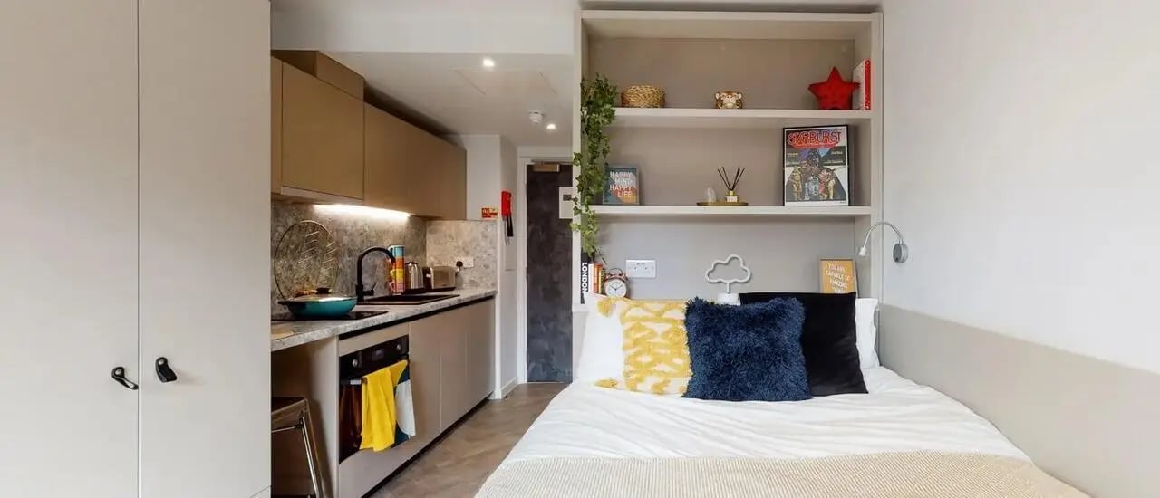 Kitchen and bed with pillows study area bedroom at Chapter Westminster in London Student Accommodation