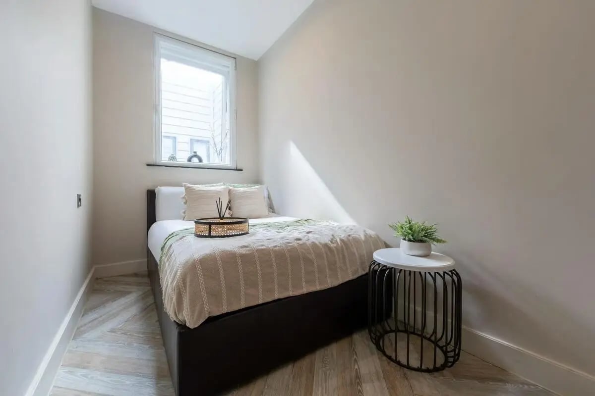 Bed with pillows side table and plant bedroom at dwell 121 Princess Street in Manchester Student Accommodation