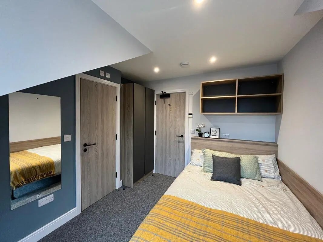 Bed with yellow blanket mirror and closet bedroom at Commercial Point Nottingham in Nottingham Student Accommodation