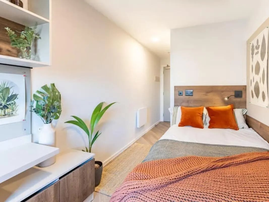 Bed with orange pillows and plants bedroom at The Place in Nottingham Student Accommodation
