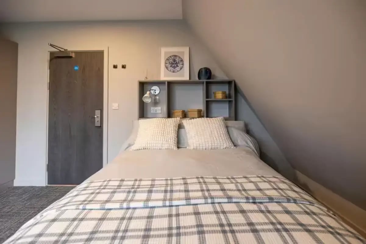 Bed with plaid throw and pillows Bedroom at Ash Grove Court - Guildford in Guildford Student Accommodation