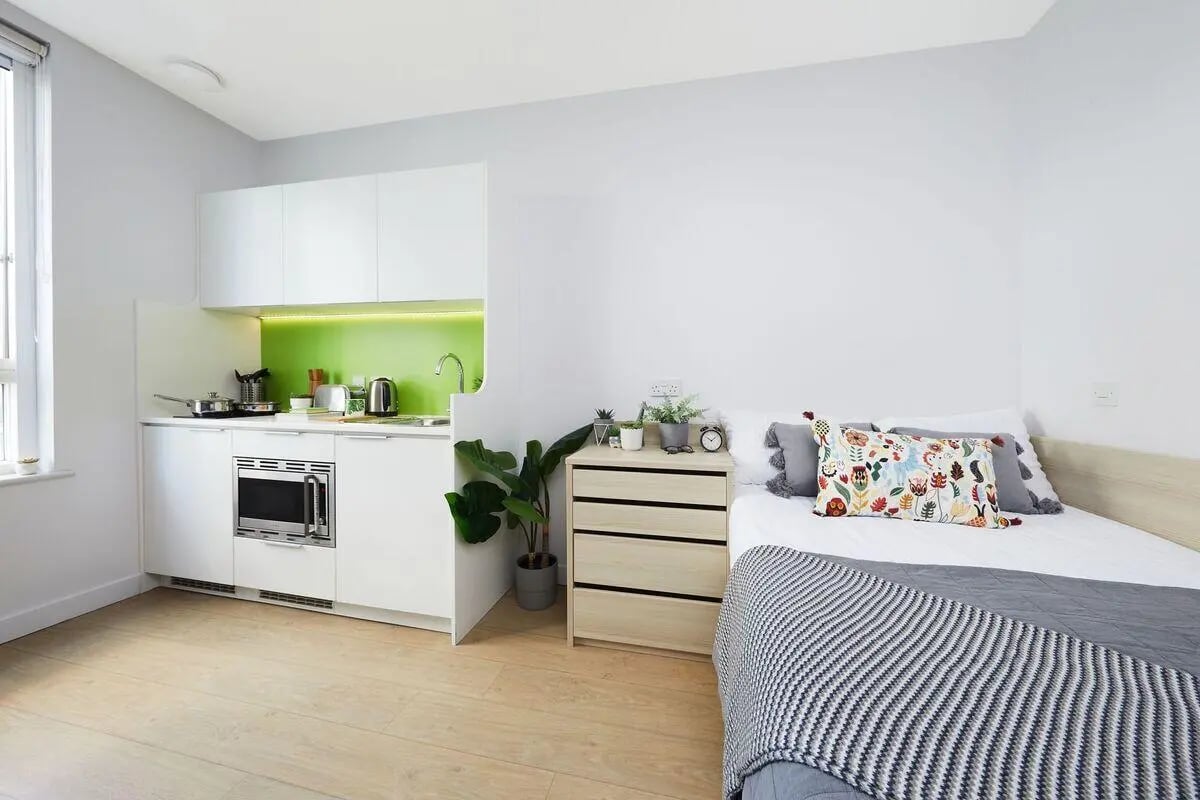 Kitchenette and bed with patterned pillows Bedroom at Collegiate Middle Street in Portsmouth Student Accommodation