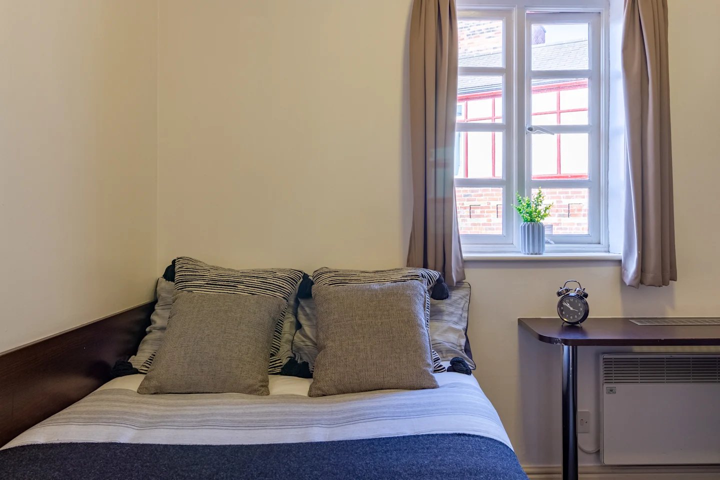 Bed with pillows curtains desk clock vase bedroom at Truro Sheffield in Sheffield Student Accommodation