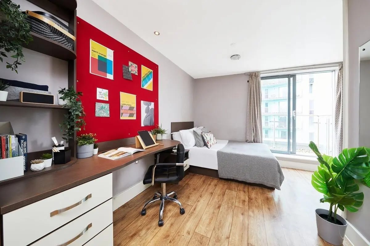 Desk chair bed plants red bulletin board bedroom at Collegiate Dashwood Studios in London Student Accommodation