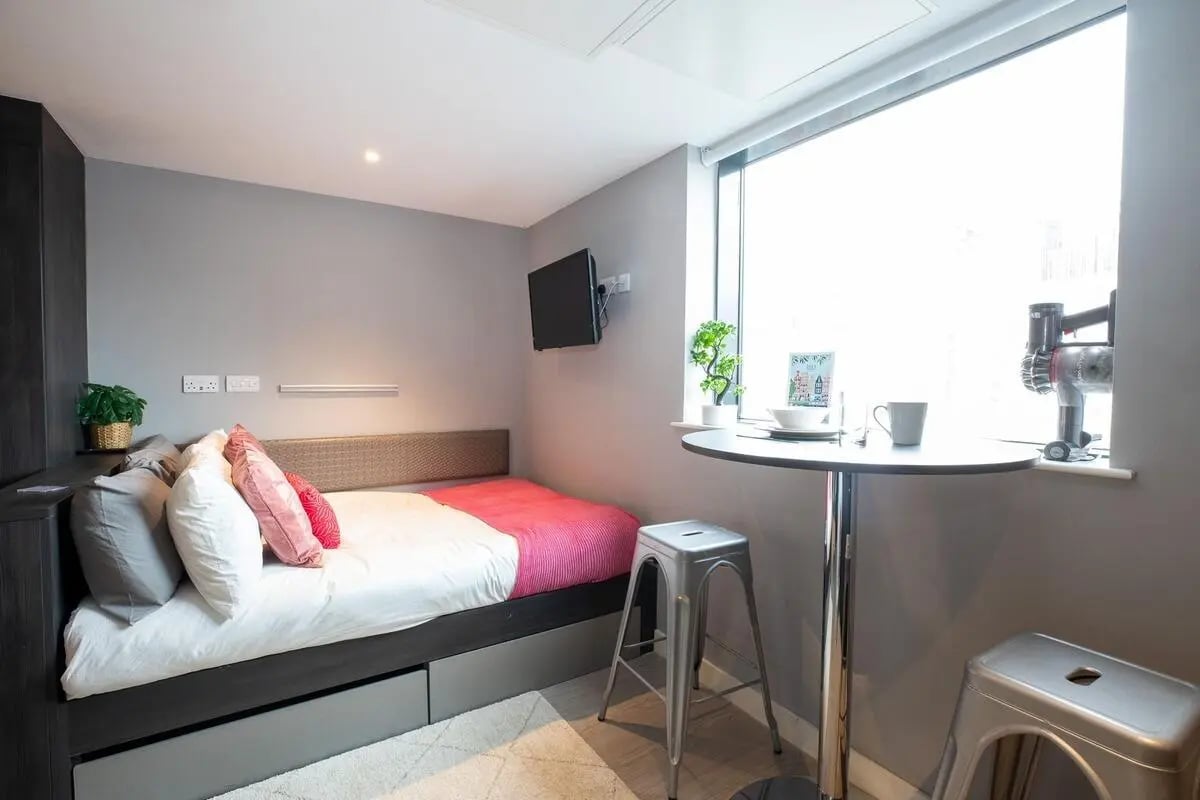 Bed with pink throw and stool at table bedroom at Collegiate Plummer House in Newcastle Upon Tyne Student Accommodation