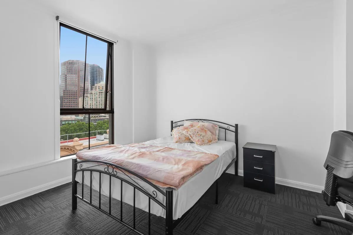 Bed nightstand chair and city view bedroom at Student Living on Flinders in Melbourne Student Accommodation