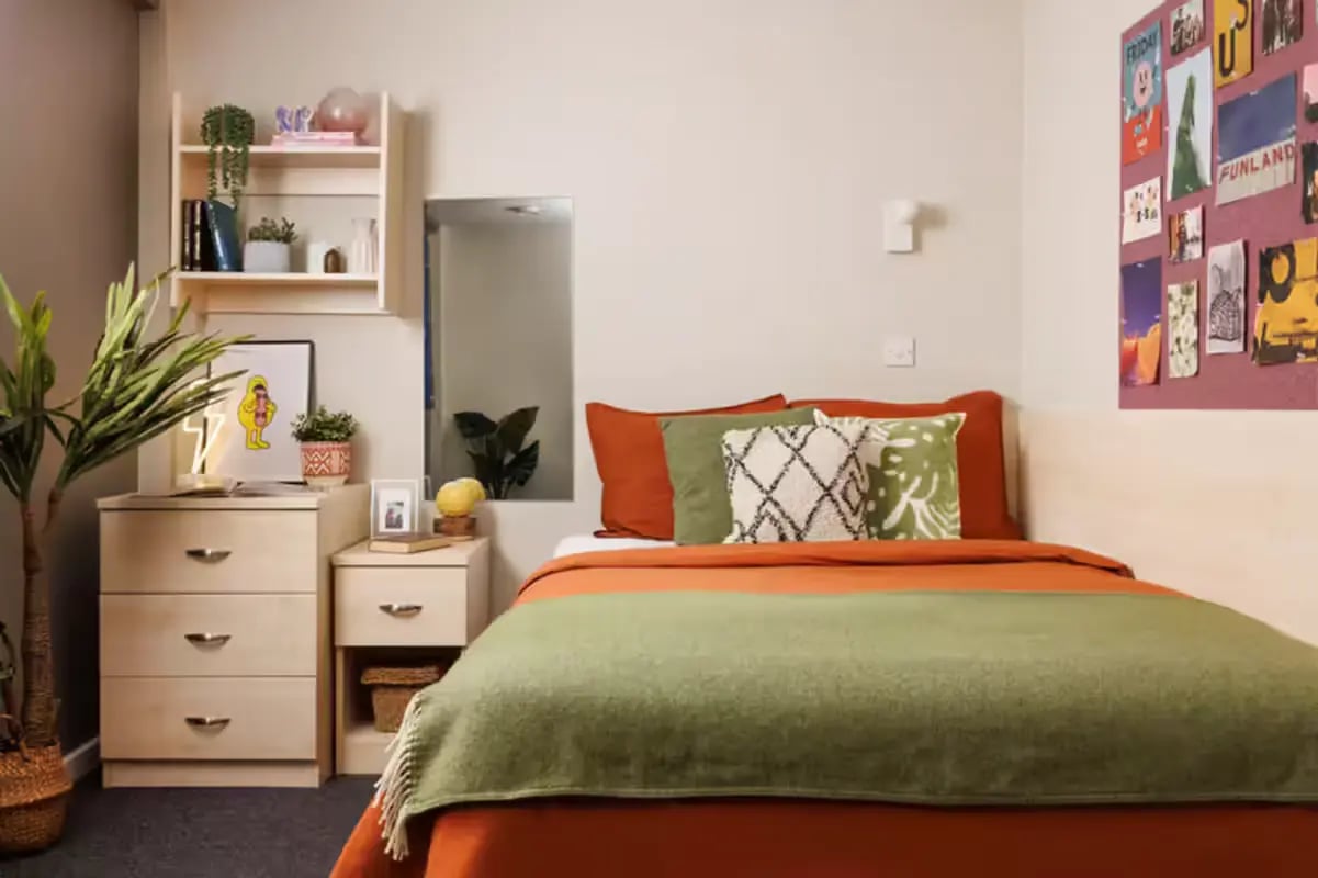 Bed with orange and green bedding artwork bedroom at The Tannery Leeds in Leeds Student Accommodation