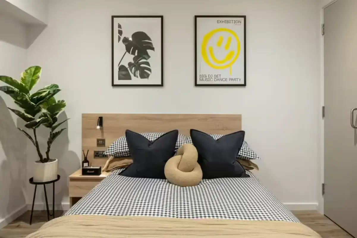 Bed with black pillows and plant Bedroom at The Fabric Works in Leeds Student Accommodation