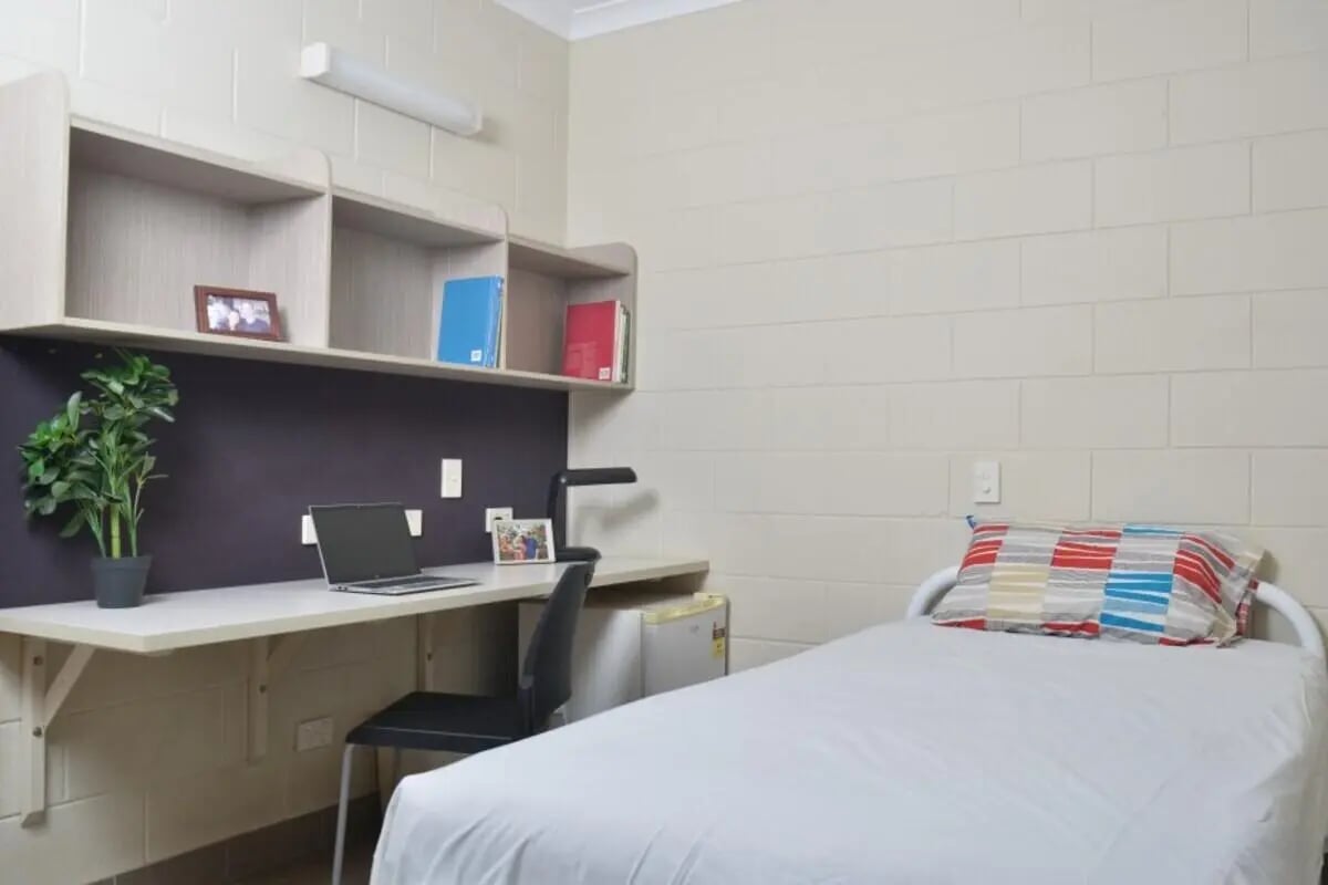 Bed desk laptop chair plant and shelves bedroom at CDU Village Casuarina in Darwin Student Accommodation